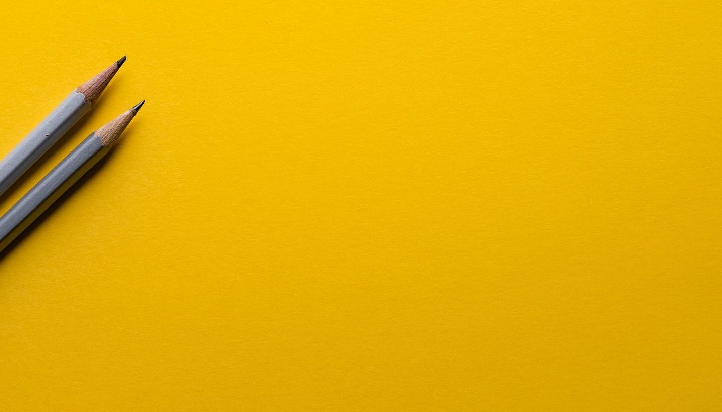 Two pencils on a yellow background
